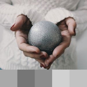 A color palette created from a close up image of a person in a white sweater holding a grey ball in their hands
