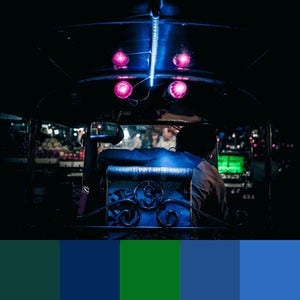 A color palette created from an image of a person sitting in front of a lit up blue and green switchboard in the dark