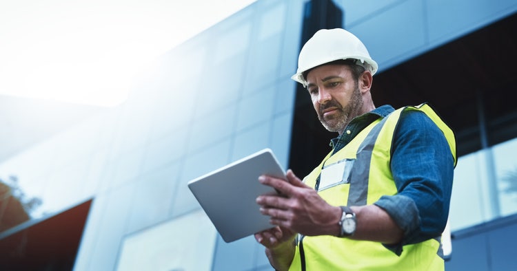 A worker at a construction site uses a tablet to apply for a conditional use permit.