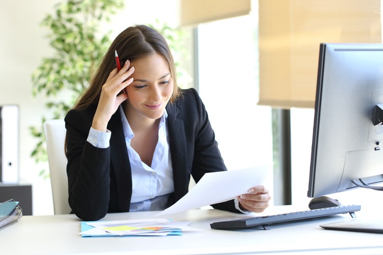 A woman reviews a bill of sale at their desk.