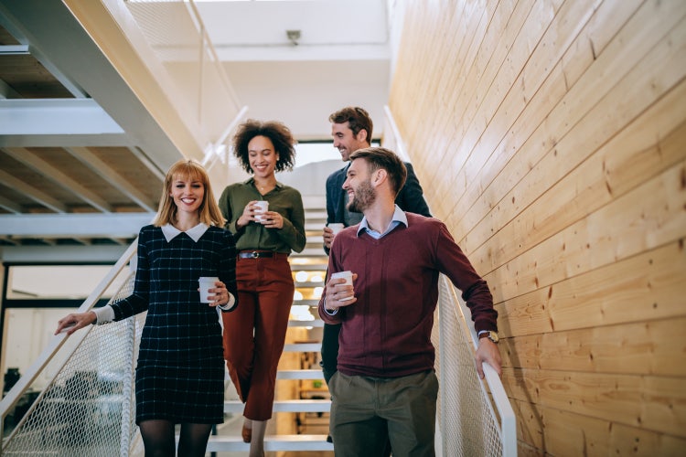 A group of four employees walk down the stairs at an office that uses effective employee retention strategies