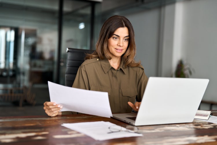 A woman creates an invoice for consulting services on her laptop.