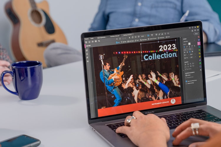 Three people working through the RFP process steps using a laptop with a blue mug on the table and an acoustic guitar in the background.