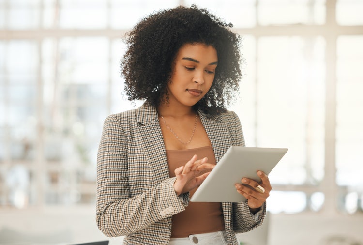 A woman uses a tablet to add a digital signature to a document as part of a signature automation process.