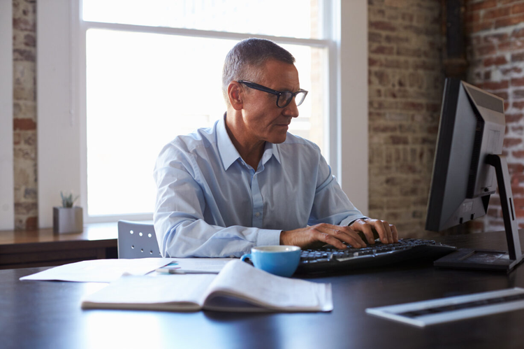 A man uses his computer to learn how to charge late fees on invoices.