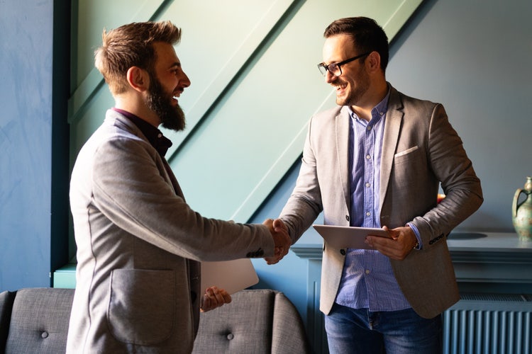 Two men shake hands after creating a general partnership agreement for their new business.