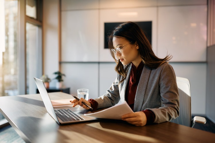 A woman uses her laptop to understand the different types of invoices.