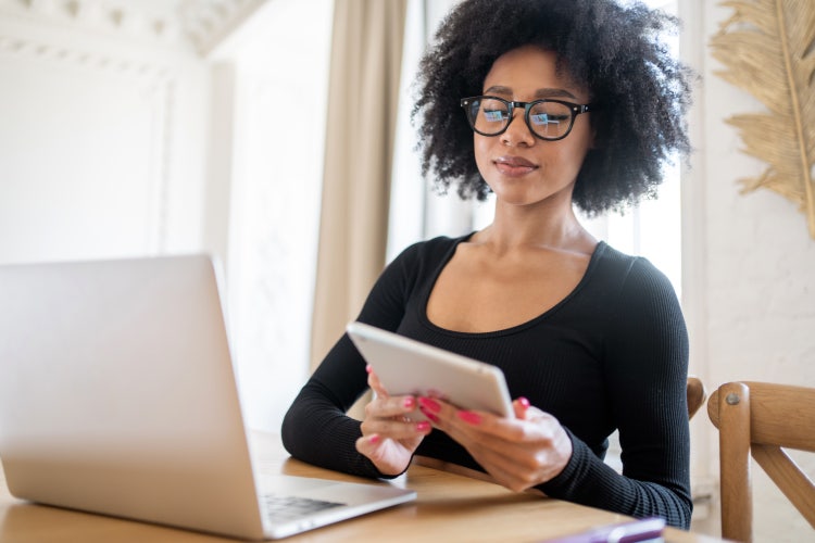 A woman uses a tablet and a laptop to learn about workflow automation