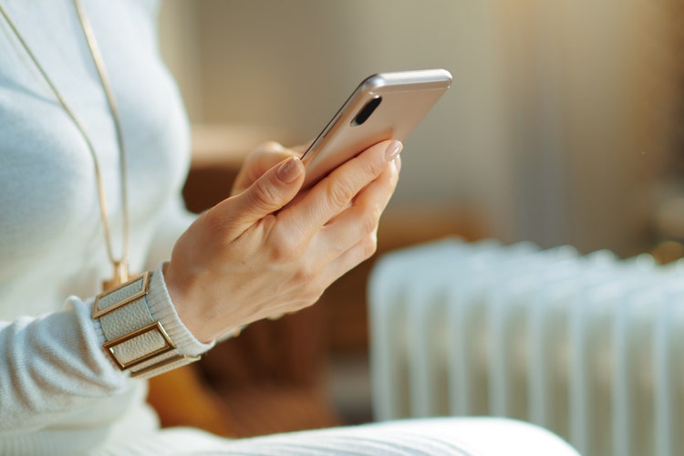 A woman's hand is shown holding a smartphone.