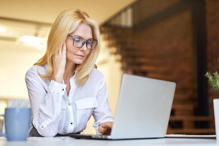 A woman uses her laptop to learn what a workforce management software is.