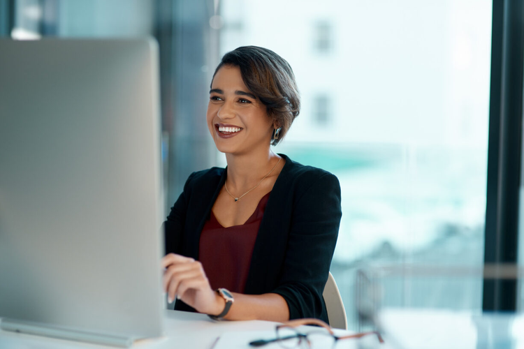 A woman in an office uses her computer to send an invoice.