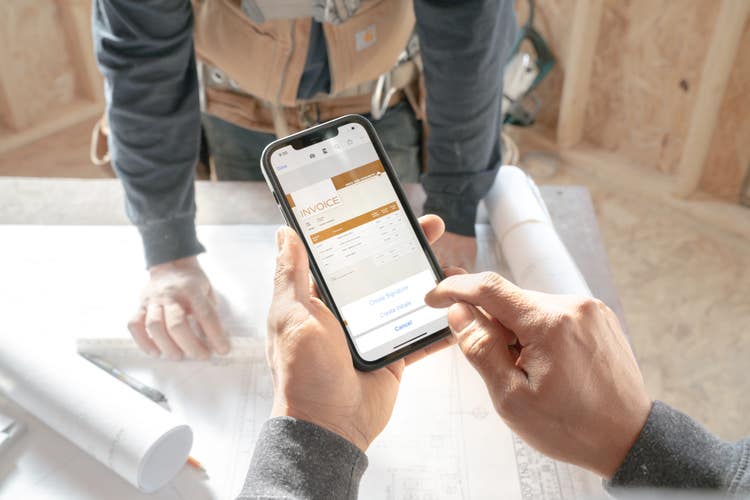 A contractor is using a smartphone to check the progress billings of a construction project invoice.