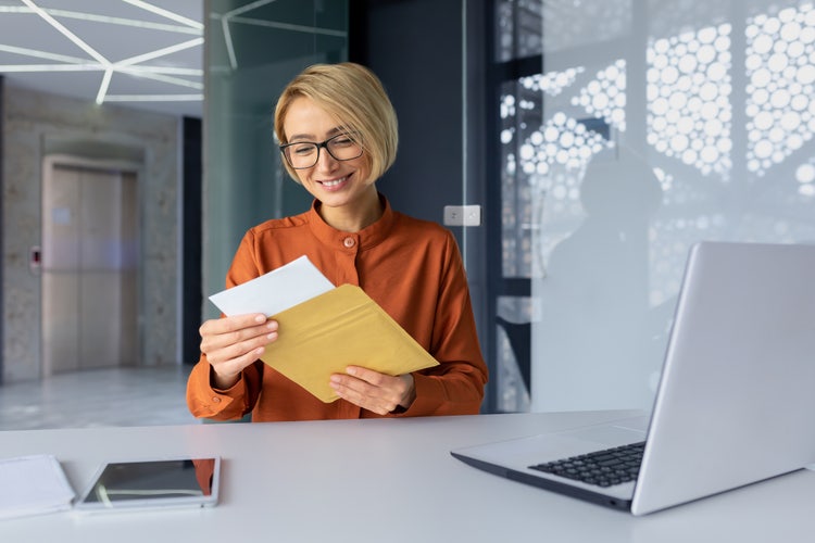 A woman sitting at a table looks at a certificate of good standing.