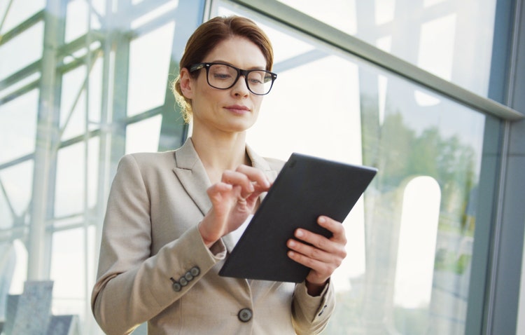 A woman uses her tablet to look up the differences between UETA vs the E-Sign Act.