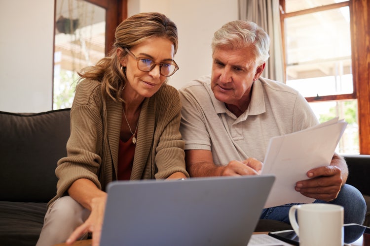 A man and a woman sit on a couch looking at a laptop resting on a table and review if they can back out of a contract easily.