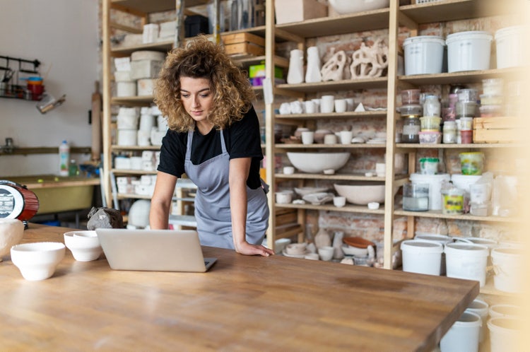 A woman standing in a retail store uses a laptop to view her small business digital transformation roadmap.