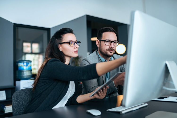 Two co-workers go over a proposal software.