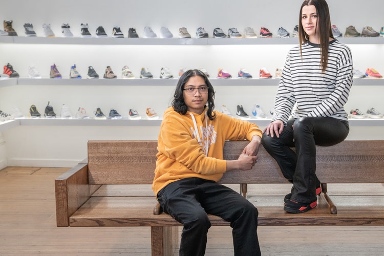 Two people sitting on a wooden bench in a shoe store thinking about making a new hire checklist template PDF for employee onboarding.