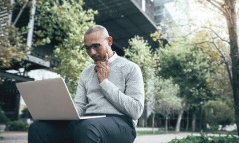 Man sitting down looking at his laptop