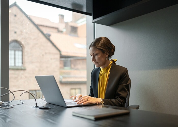 A photo of a person sitting at a desk working on a laptop computer.