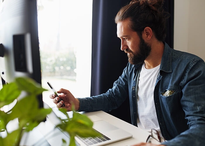 A photo of a person sitting at a desk in an office and working on a laptop computer.