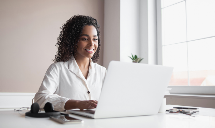 A woman sitting at a desk types on her laptop.