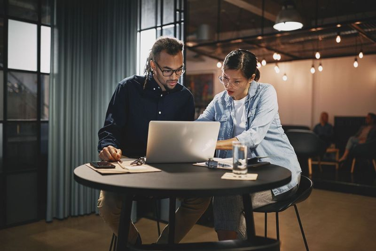 A man and woman sitting at a table look at a memorandum of understanding on a laptop.