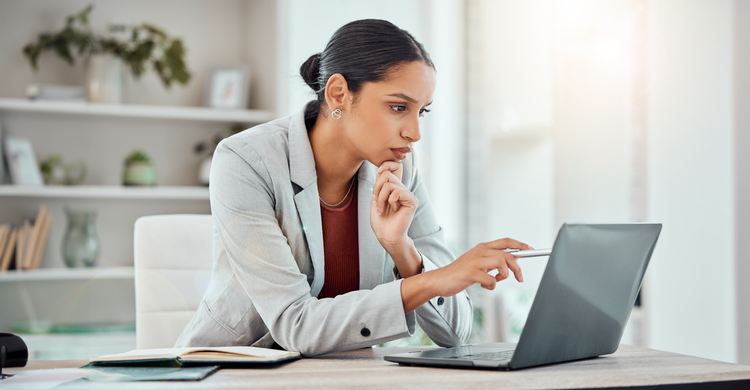 A woman sitting at a desk looks at a non-disclosure agreement on her laptop.