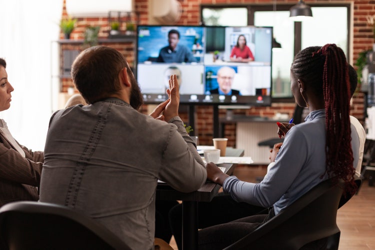 A team collaborates remotely from a conference room and on video chat.