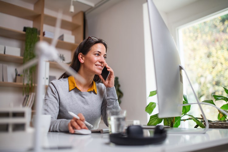 Woman talks on the phone about strategies for sustainability in business while working on her computer.