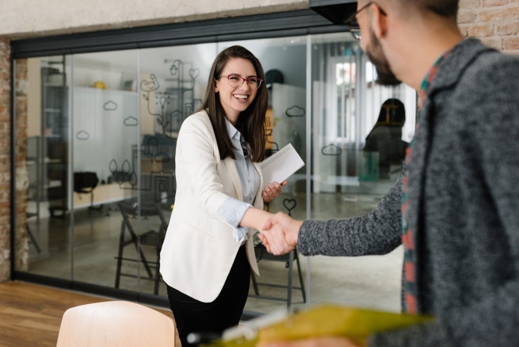 A businesswoman exchanging handshakes with a man in an office during their job hunting process.