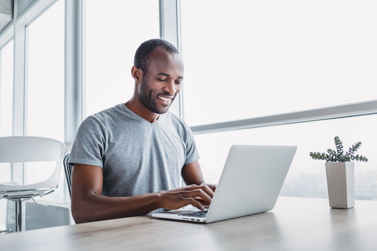 A man sitting at a table collaborates on PDF documents on his laptop.