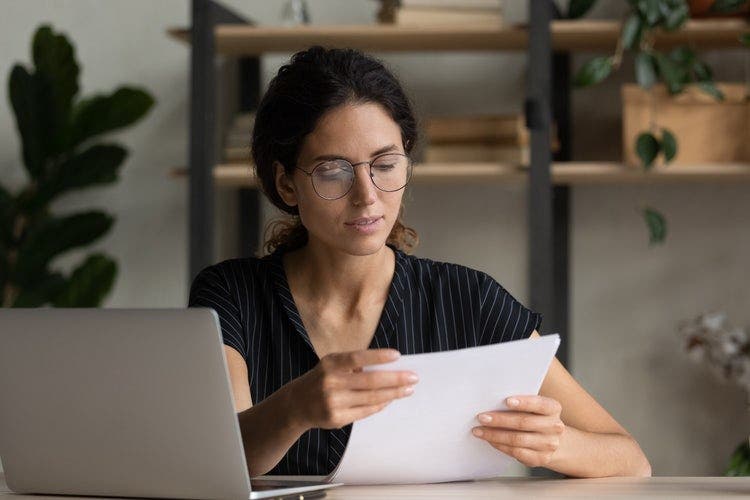 A woman writes a cover letter template at her desk.