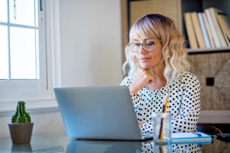 A woman uses her laptop to create an event planning contract template.