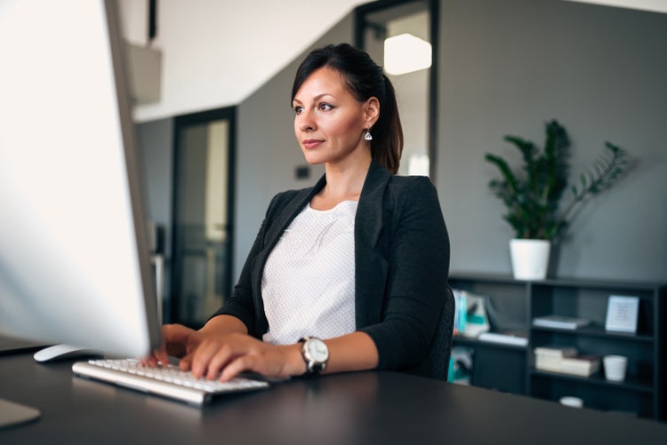 A woman uses remote productivity tools on her home desktop computer.