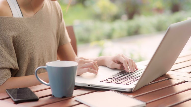 A woman uses her laptop to add page numbers to her Word document.