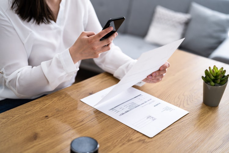 A woman scans receipts using her smart phone so she can organize them digitally for taxes.