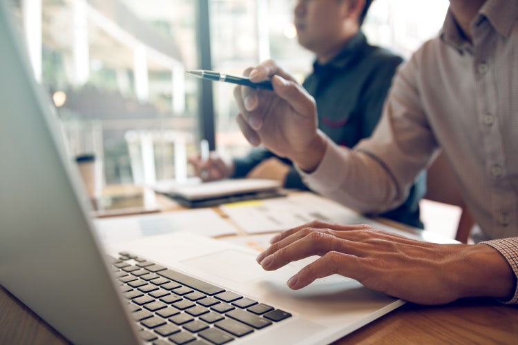 Two people working collaboratively on a shared to-do list at a table with a laptop.