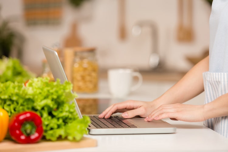 A person in a kitchen uses a laptop to convert a recipe to change the yield and size.