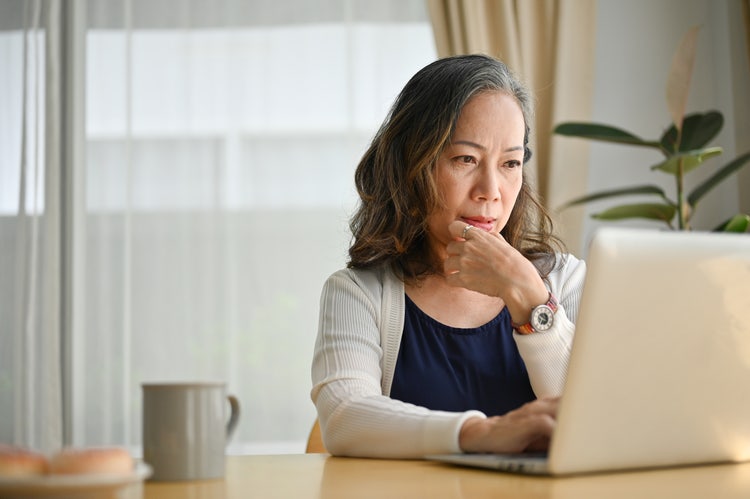 A woman sitting at a table secures a PDF file on her laptop.