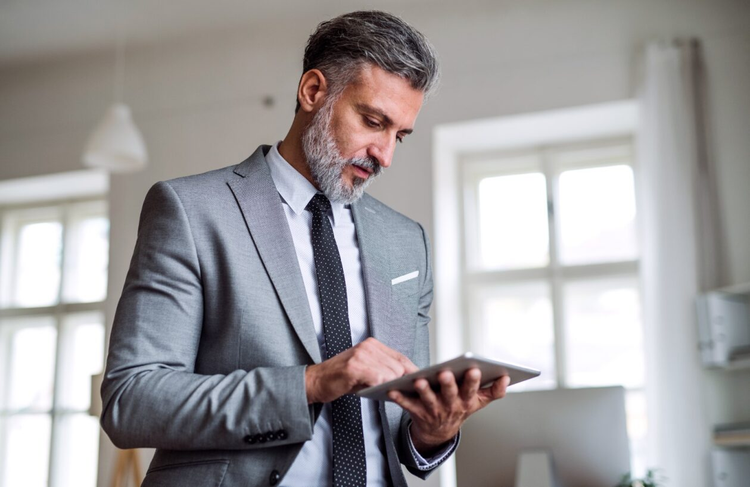 A man in a gray suit holds a tablet and learns how to fill out an aircraft bill of sale form.