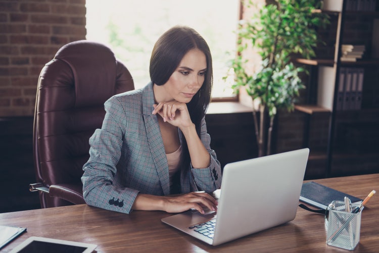 A woman sitting at a desk works on a pre-listing checklist for real estate.