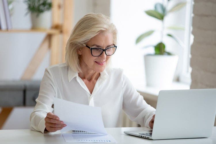 A woman sitting at a desk types on her laptop.