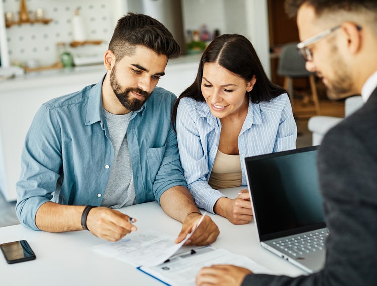 A man and a woman reviewing the terms of a bill of sale and title for a car they are purchasing.