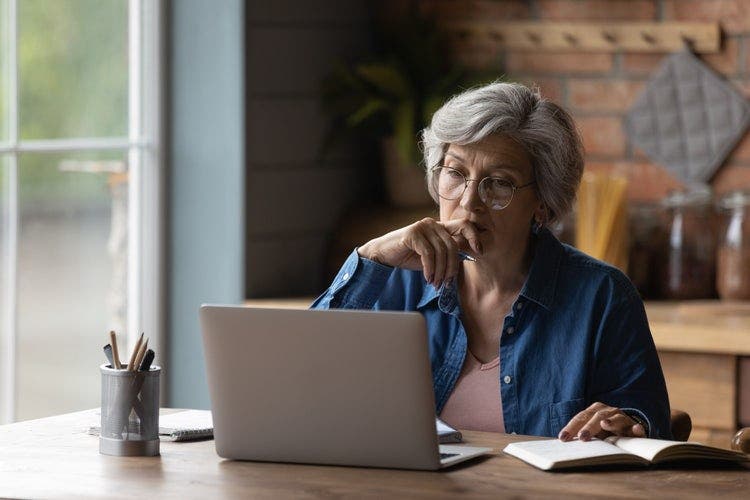 A woman in a kitchen uses her laptop to edit a PDF in Word.