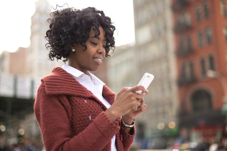 A woman walking outside deletes pages from a PDF file using an iPhone.