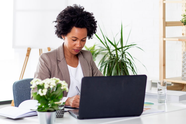 A woman uses her laptop to write a bill of sale for real estate.