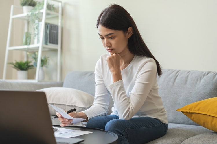 A young woman looks at financial documents to develop a zero-based budget.