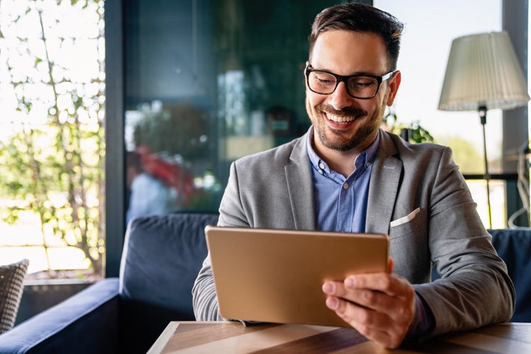 A man uses a tablet to sign a bank document electronically.