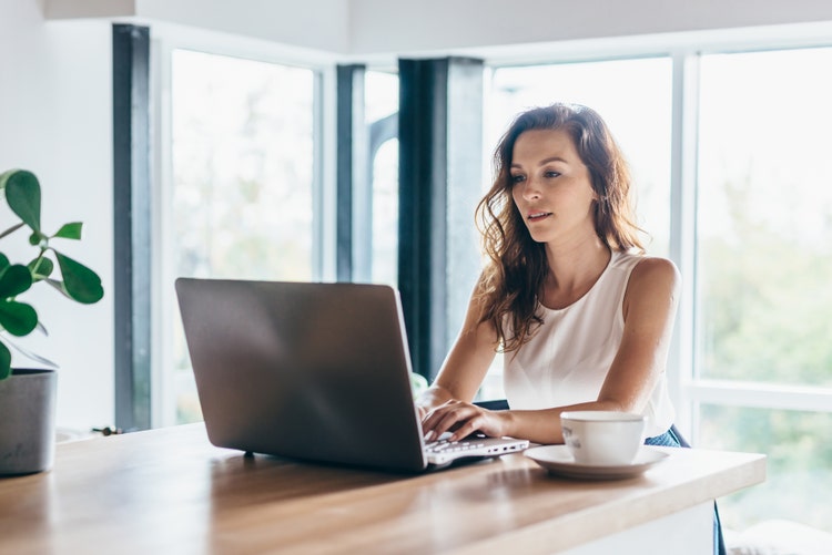 A woman researches online collaboration tool software on a laptop computer.